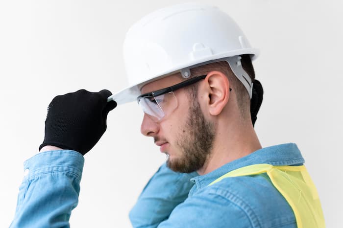Homme portant un casque de sécurité, des lunettes de protection et un gilet réfléchissant