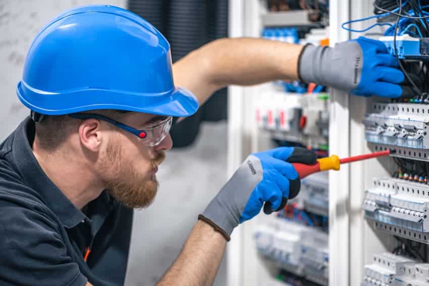 Technicien portant un casque de sécurité intervenant sur un tableau électrique dans le cadre d’une formation H0B0 pour prévenir les risques électriques.