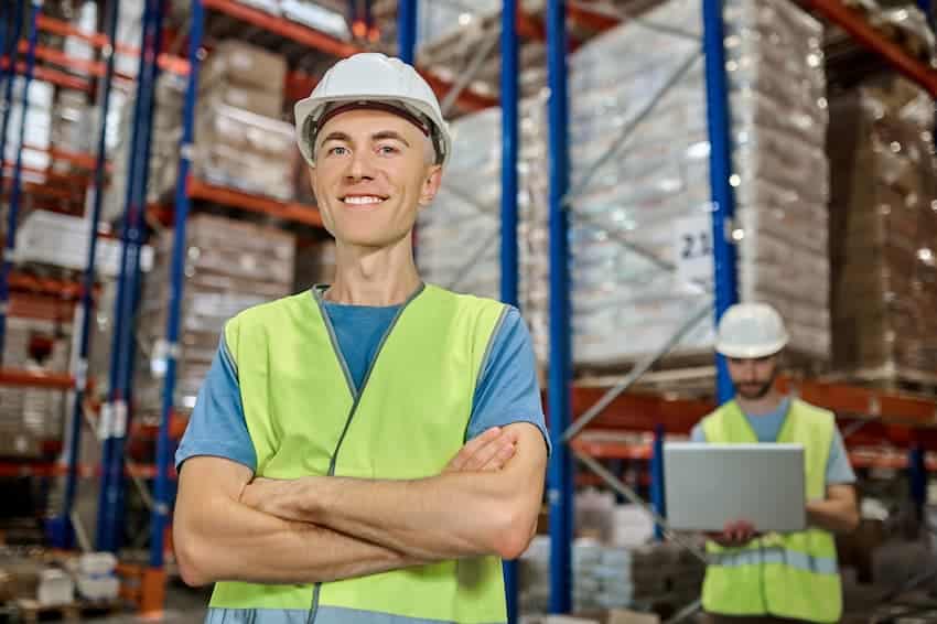 Responsable logistique en gilet de sécurité dans un entrepôt industriel, illustrant la prévention des risques physiques en formation PRAP IBC.