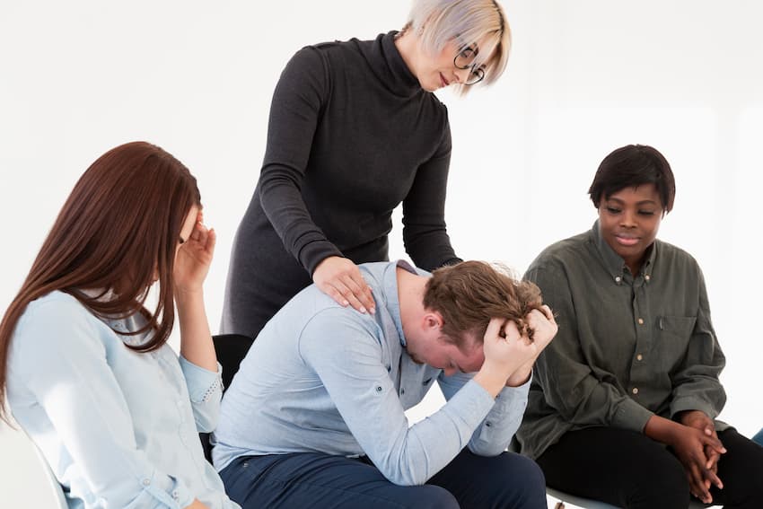 Professionnel en situation de détresse soutenu par ses collègues lors d'une session de prévention des risques psychosociaux en entreprise.