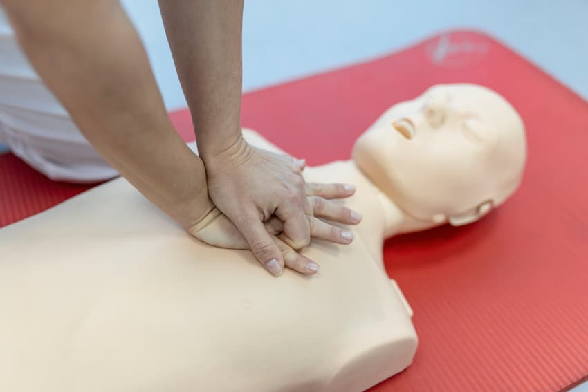 Stagiaire pratiquant les compressions thoraciques sur mannequin lors d'une comparaison des formations SST et PSC1 en premiers secours.
