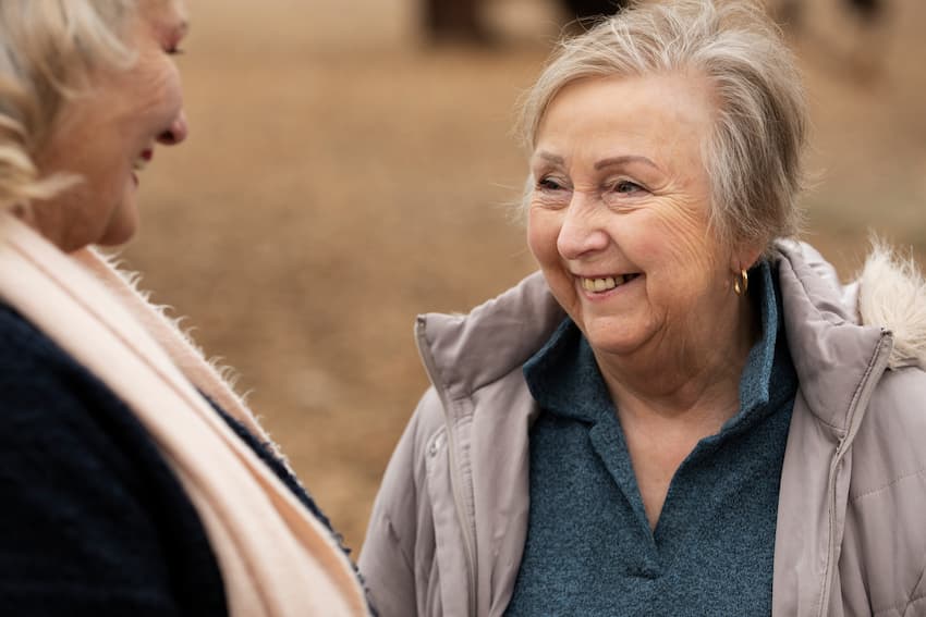 Deux femmes âgées échangeant avec bienveillance à l'extérieur, illustrant la relation de confiance et le respect de la dignité au cœur de la bientraitance en EHPAD.