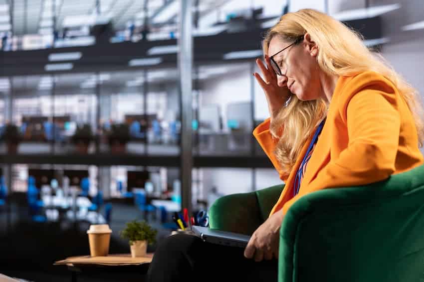 Cadre ou dirigeante visiblement en état de surcharge ou d'épuisement professionnel, illustrant les effets du stress, de la fatigue décisionnelle ou des conditions de travail dégradées sur les personnes en position d'encadrement.