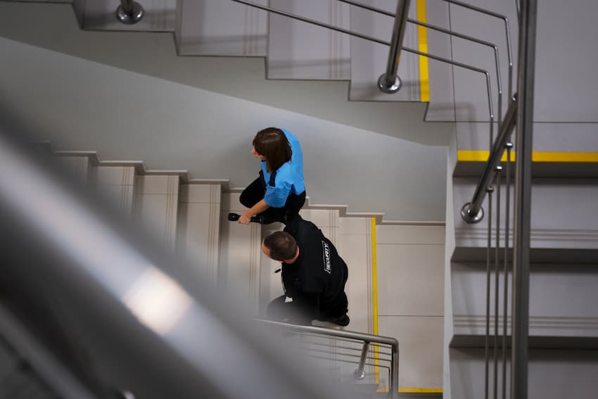 Personnes empruntant un escalier de secours dans un bâtiment, illustrant l'organisation des cheminements d'évacuation incendie et le rôle des guides et serre-files.