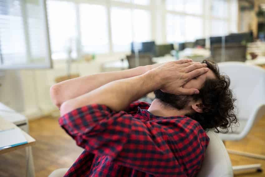 Professionnel submergé, le visage entre les mains, traduisant l'épuisement et la pression liés à la charge de travail.