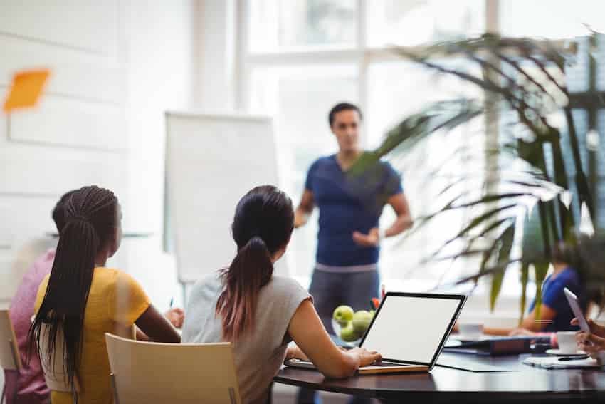 Formateur animant une session devant un groupe de salariés en salle, illustrant la mise en œuvre du plan de formation prévention en entreprise.