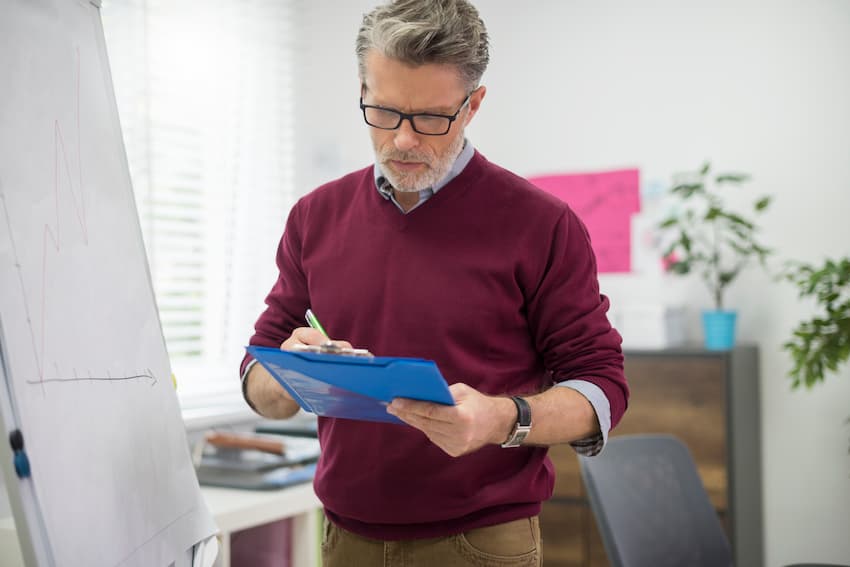 Formateur prenant des notes sur un porte-documents à côté d'un paperboard.