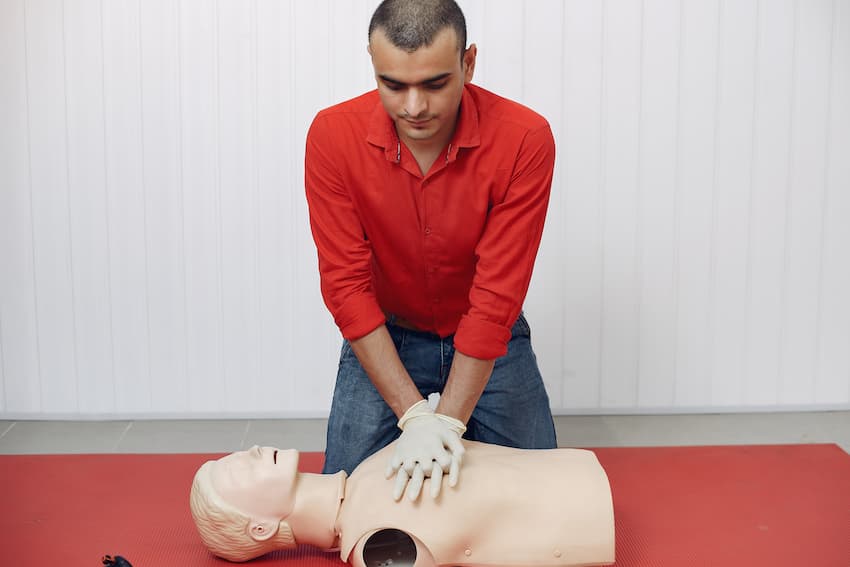 Stagiaire pratiquant un massage cardiaque sur un mannequin lors d'un exercice de secourisme.