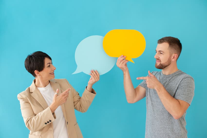 Homme et femme se faisant face avec des bulles de dialogue, symbolisant l'échange en entreprise.