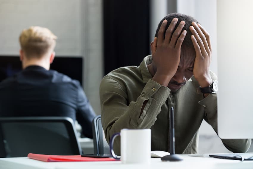 Salarié tenant sa tête entre ses mains à son poste de travail, illustrant la charge émotionnelle à évacuer après une agression au travail.