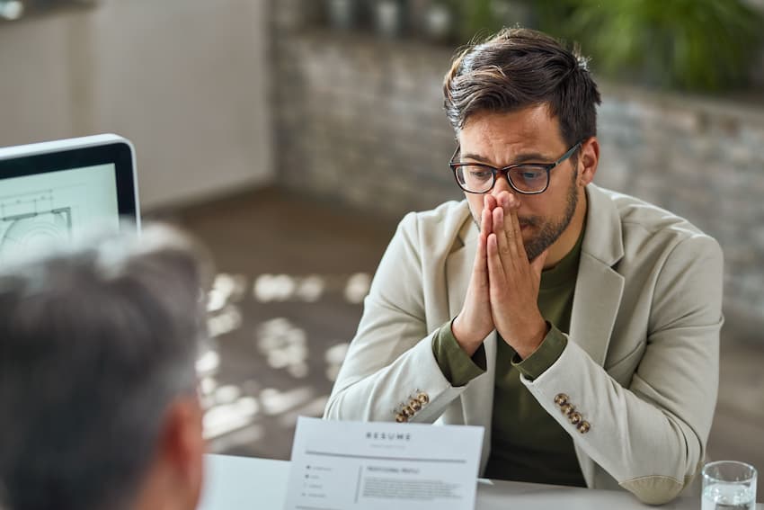 Salarié en difficulté, mains jointes devant le visage, lors d'un entretien avec un collègue.